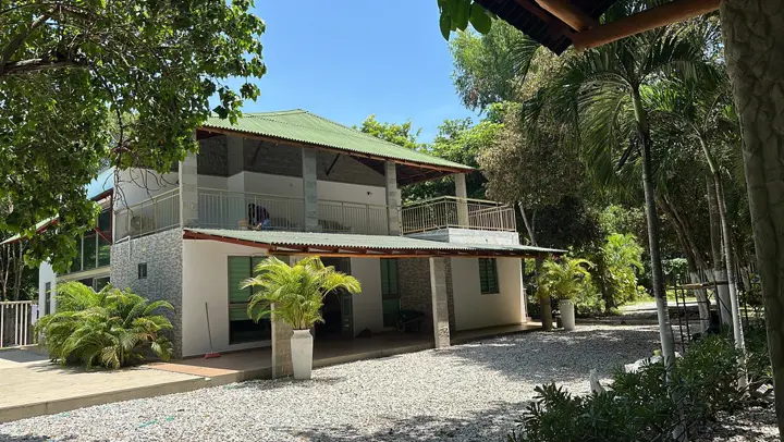 Fachada de día, rodeada de palmas y árboles